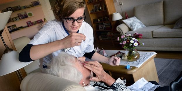 verpleegkundige helpt oude vrouw met medicijnen